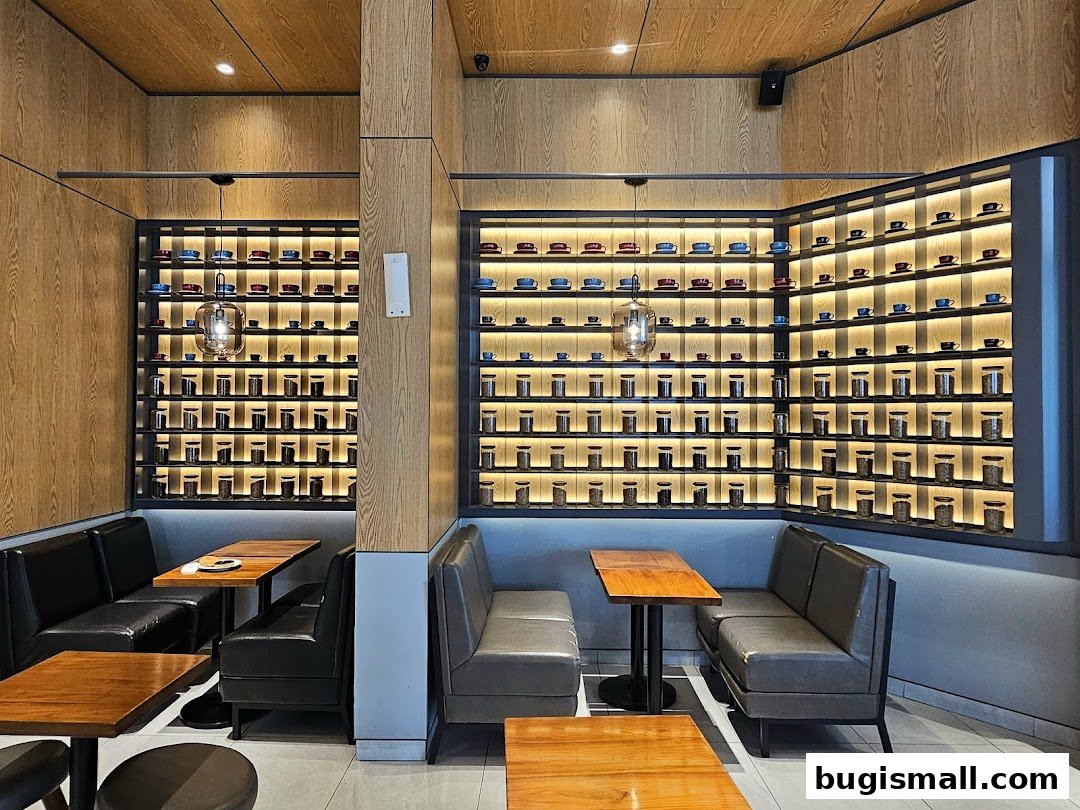 Interior of a J.CO Donuts & Coffee shop with seating and shelves displaying cups and jars.