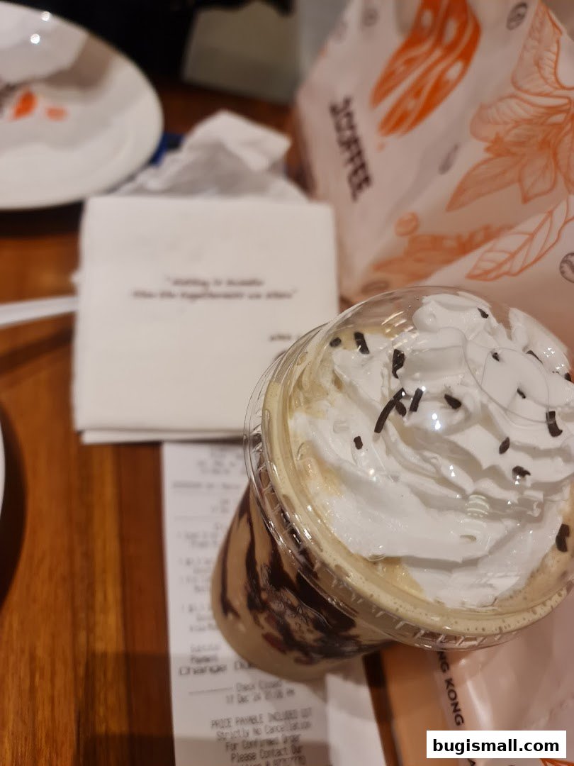A close-up of a J.CO Donuts & Coffee drink with whipped cream and chocolate drizzle.