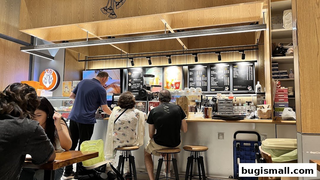 Customers are seated at a counter in a J.CO Donuts & Coffee shop, ordering from staff.