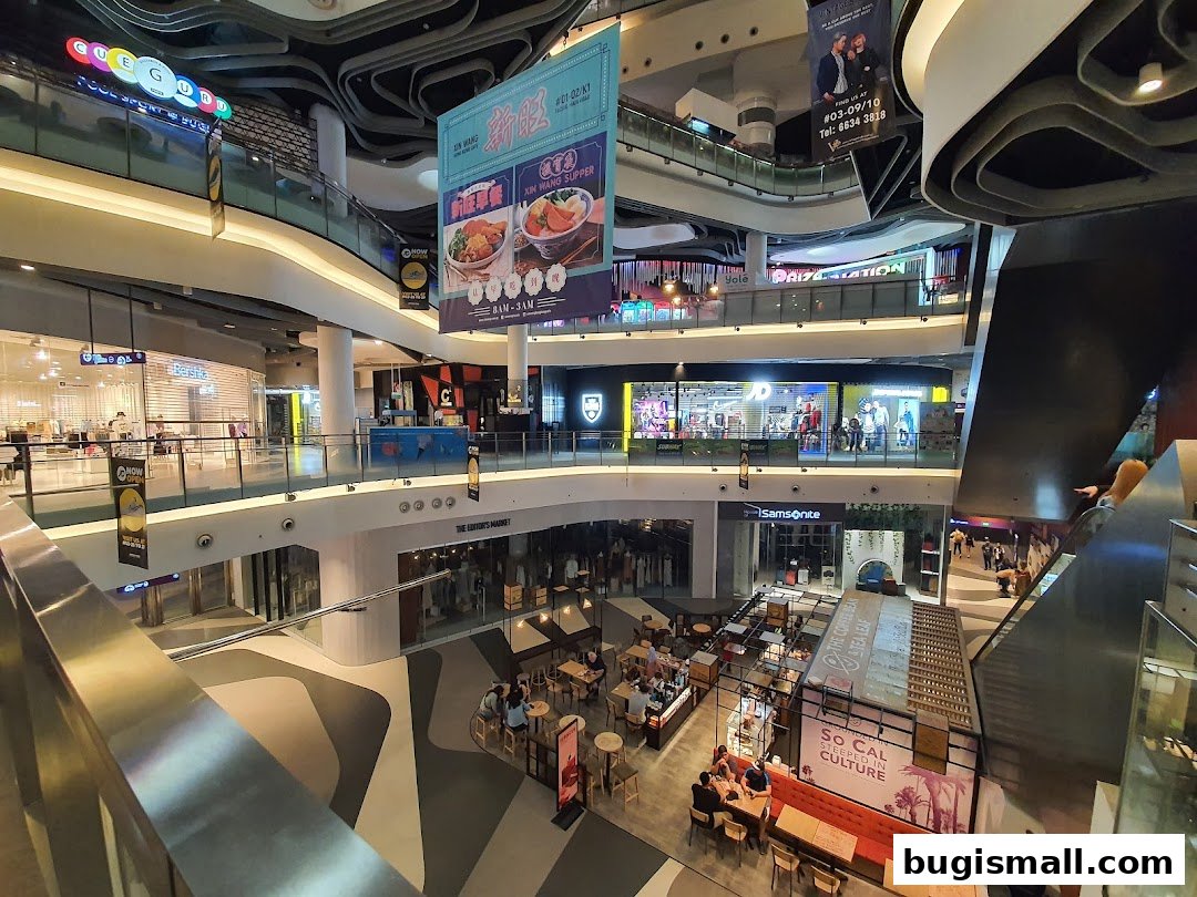 A multi-level shopping mall interior with various shops and escalators visible.