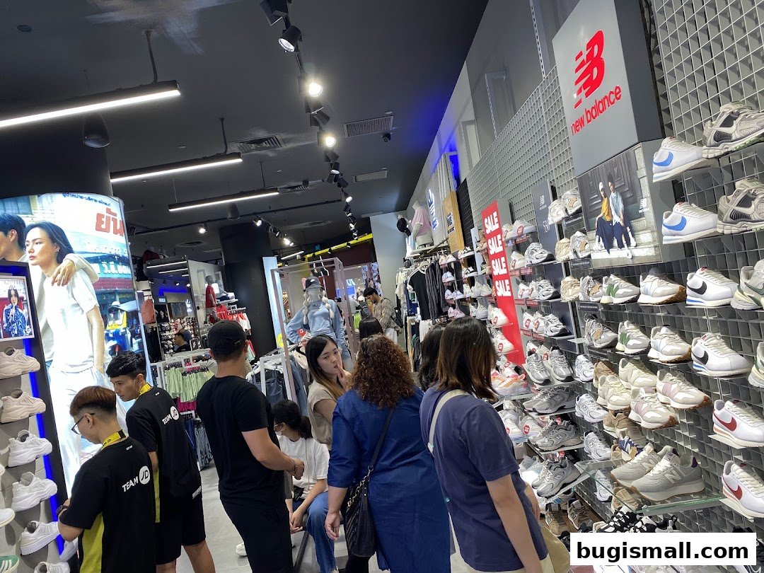Customers browse a wide selection of athletic footwear and apparel in a brightly lit JD Sports store.