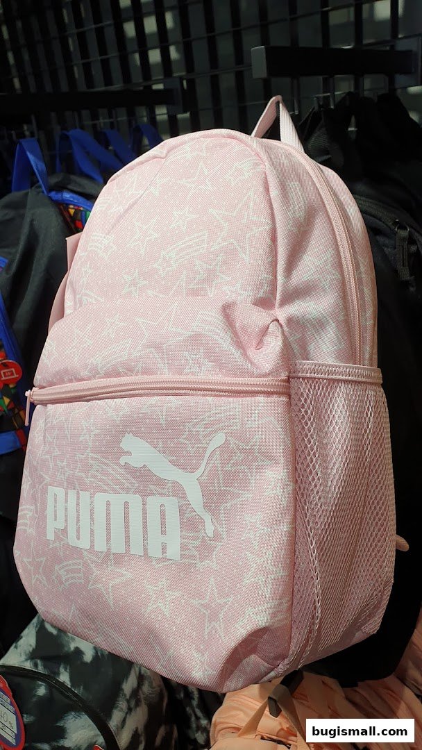 A pink Puma backpack with a star pattern is displayed in a store.