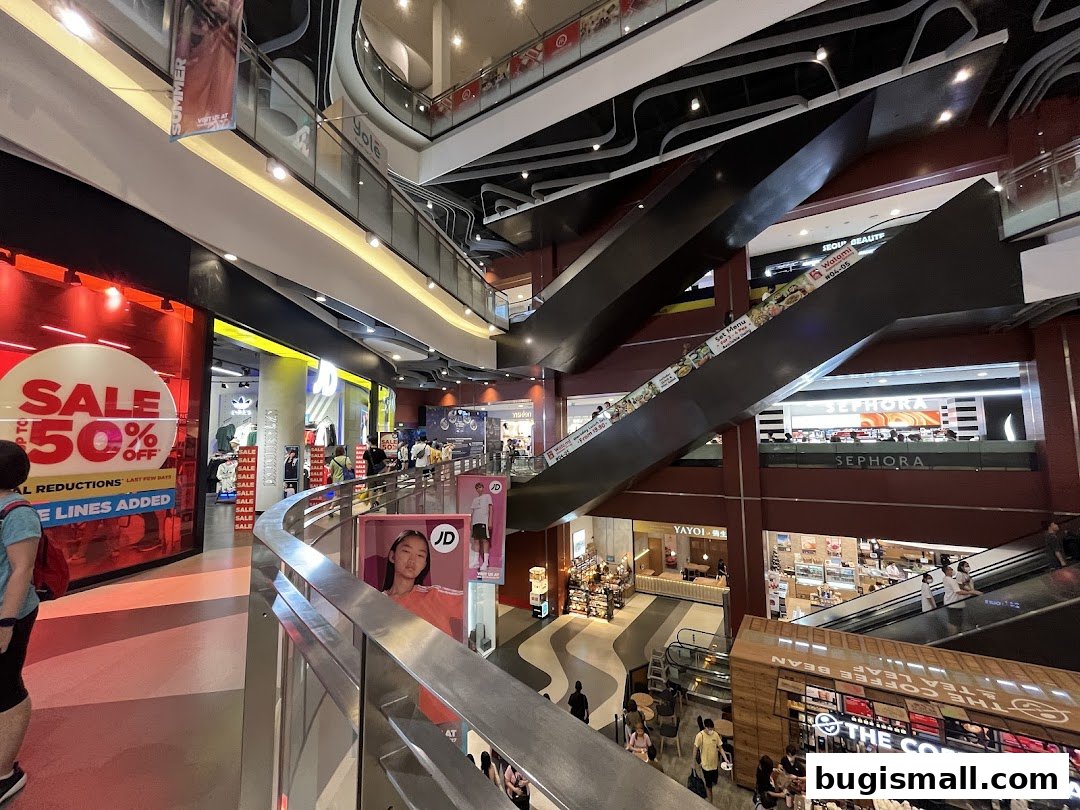 Interior view of a multi-level shopping mall with escalators and various stores.