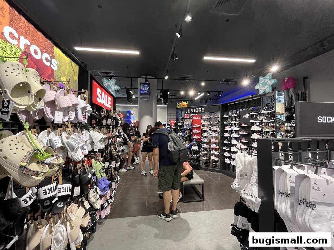 Interior view of JD Sports store showcasing a wide selection of footwear and apparel, with customers browsing.