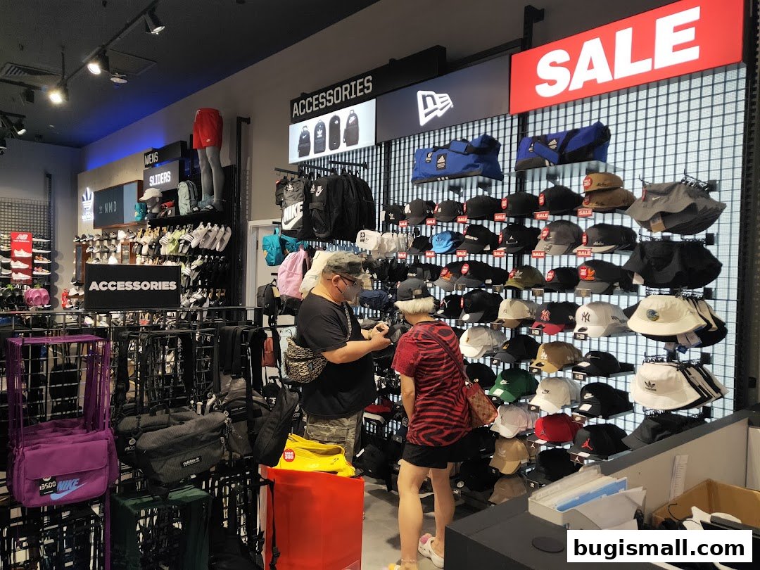 Customers browsing accessories and hats in a JD Sports store with a prominent SALE sign.