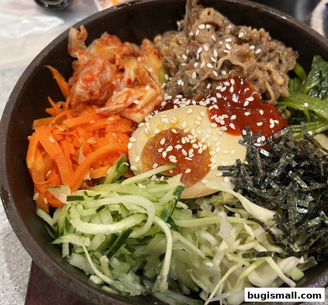 A close-up of a delicious Korean bibimbap with beef, egg, kimchi, and fresh vegetables.
