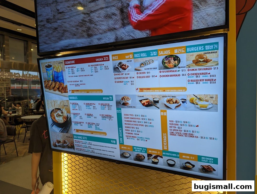 A digital menu board displaying various Korean fried chicken dishes, noodles, burgers, and beverages.