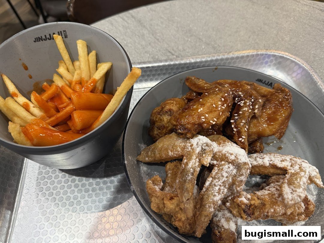 A close-up of Korean fried chicken and fries with tteokbokki.