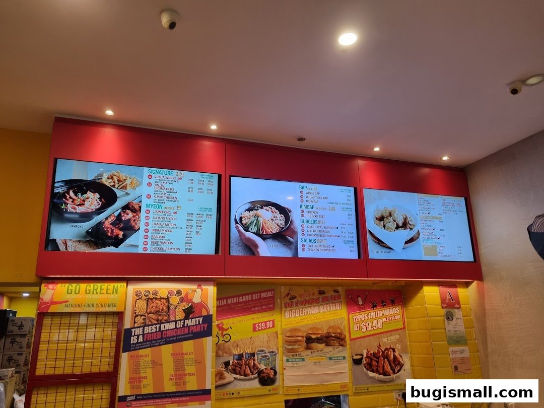 Digital menus displaying Korean fried chicken and noodle dishes at JINJJA Chicken.