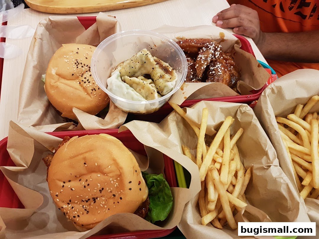 A close-up of a meal with burgers, fries, wings, and dumplings.
