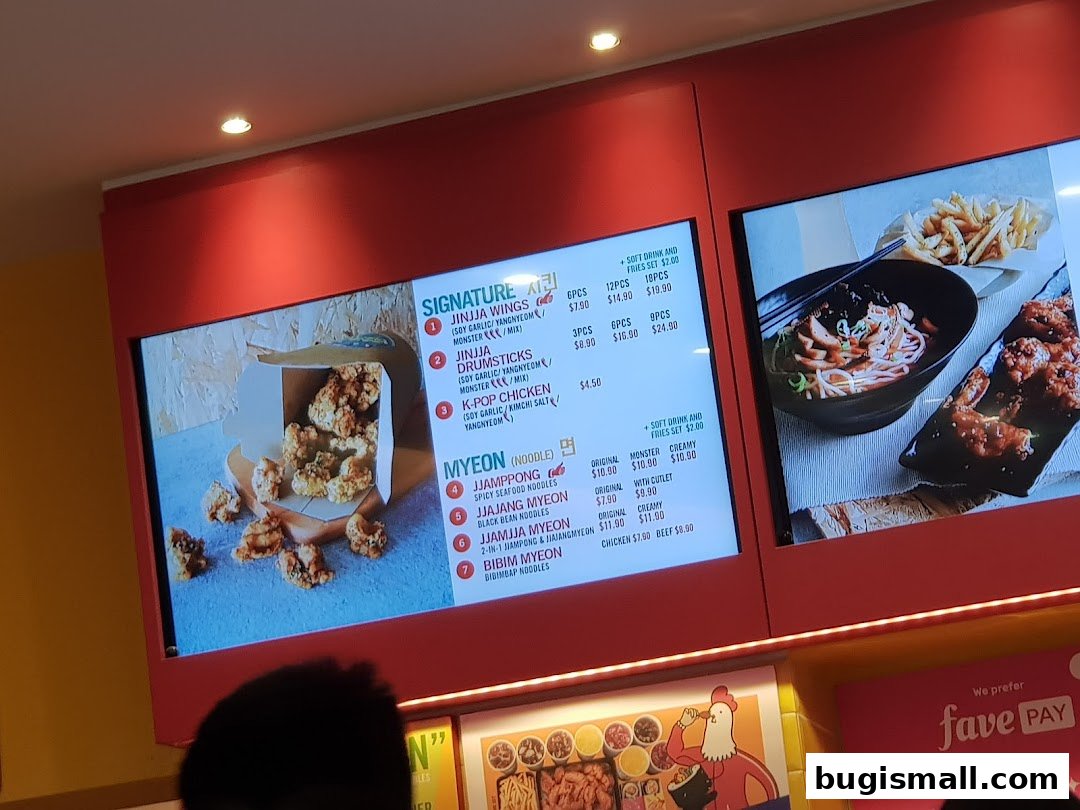 A digital menu board displaying Korean fried chicken and noodle dishes with prices.