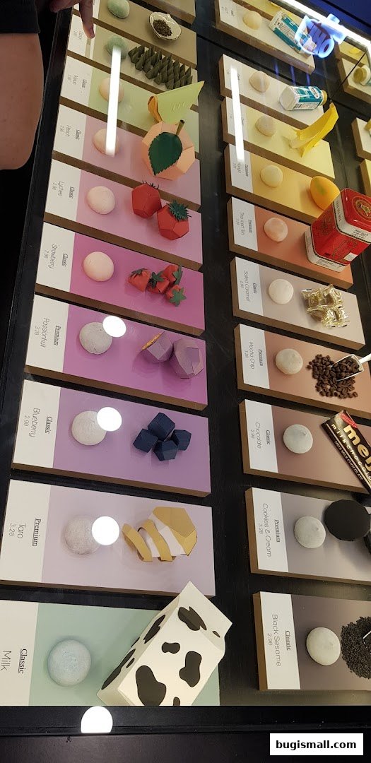 A display case showcasing various flavors of mochi with decorative papercraft.