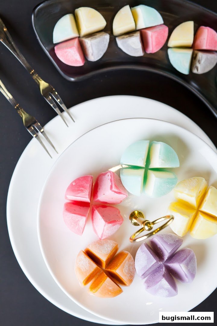 Colorful mochi desserts arranged on white plates with forks, presented for a delightful treat.