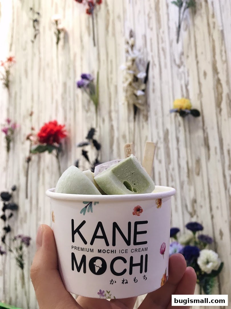 A hand holds a cup of mochi ice cream with a floral background.