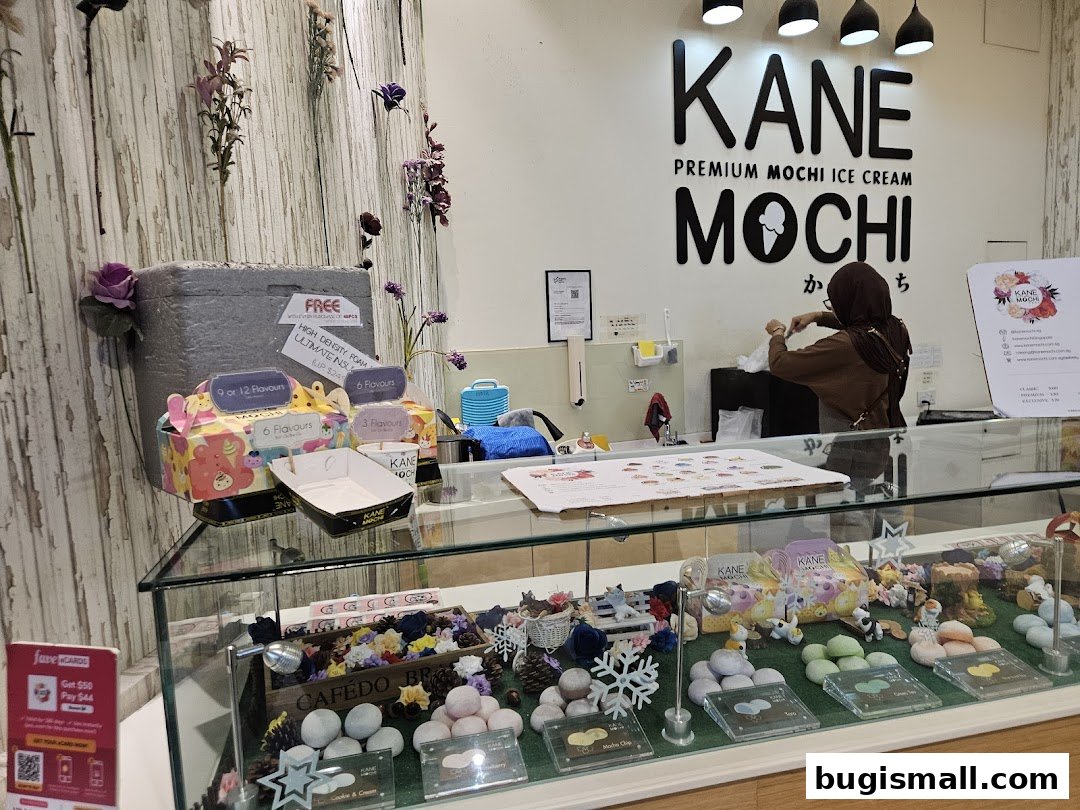 A Kane Mochi ice cream shop counter with mochi displayed and a staff member serving.