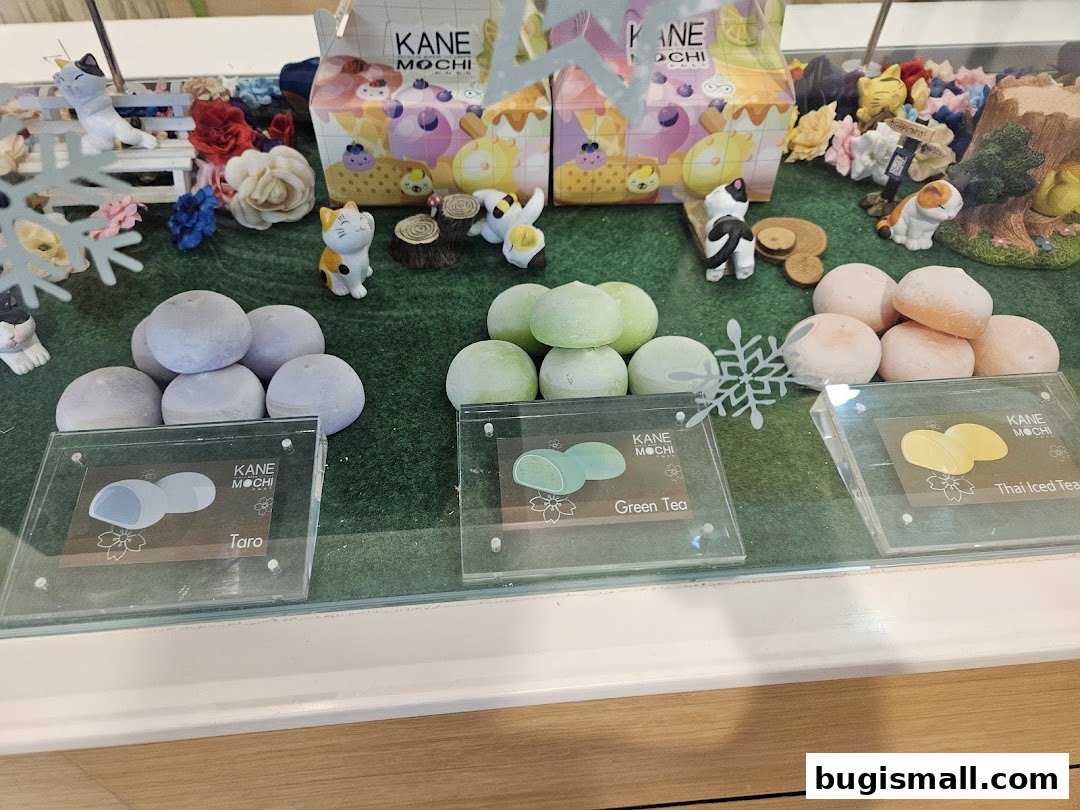 A display of colorful mochi treats with cute cat figurines and decorative elements.