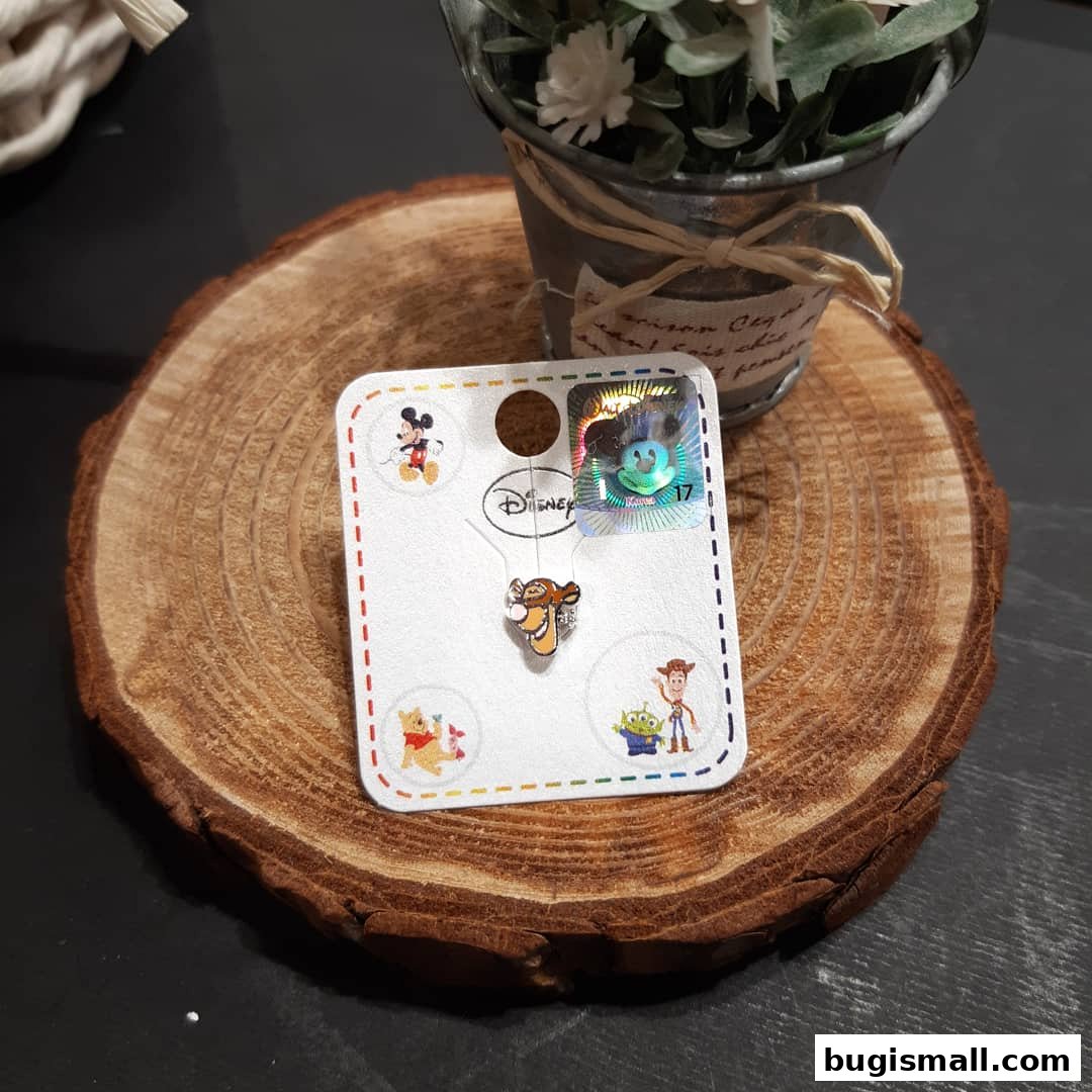 A Disney-themed pin featuring Tigger on a wooden slice with a small plant.