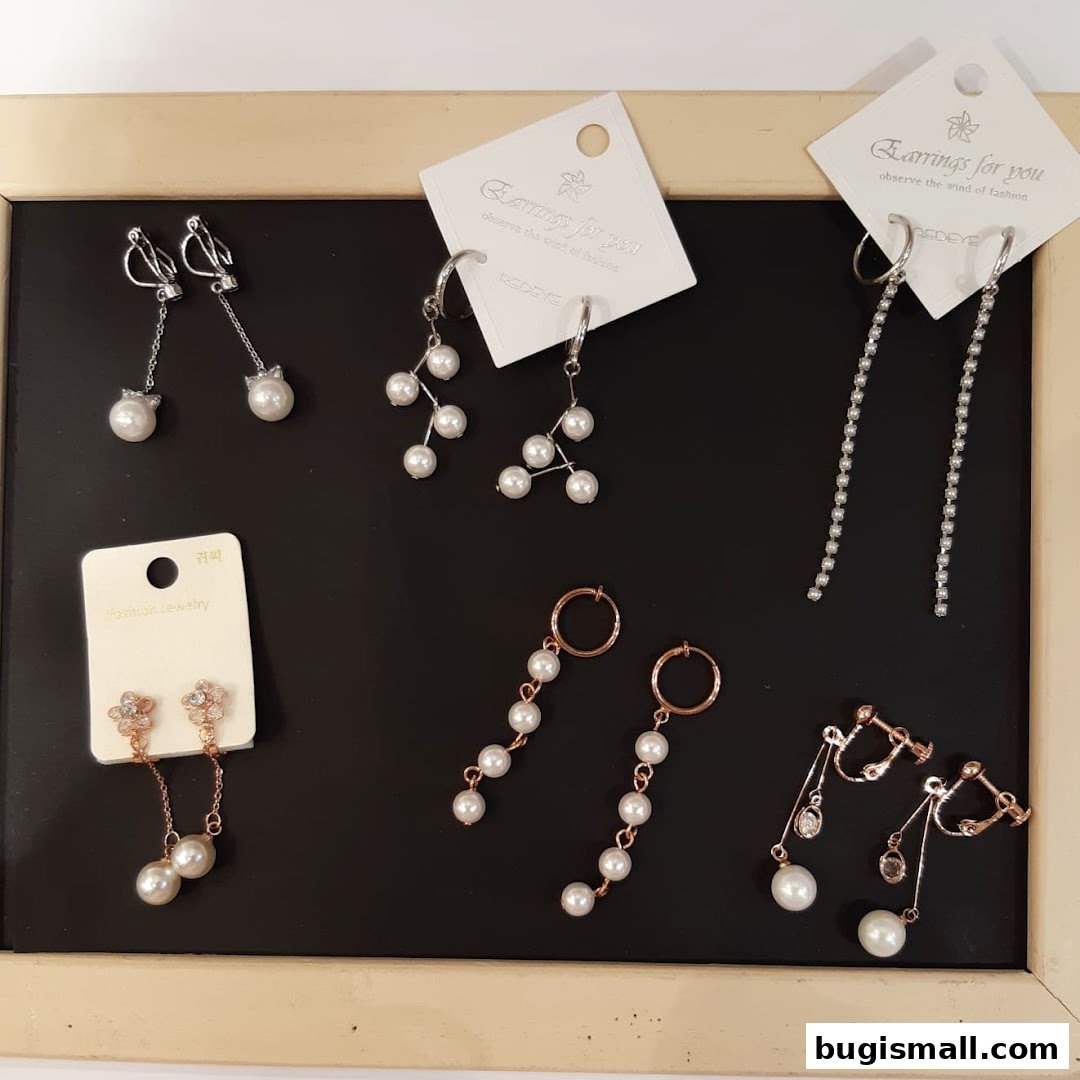A collection of various fashion earrings displayed on a black surface with a wooden frame.