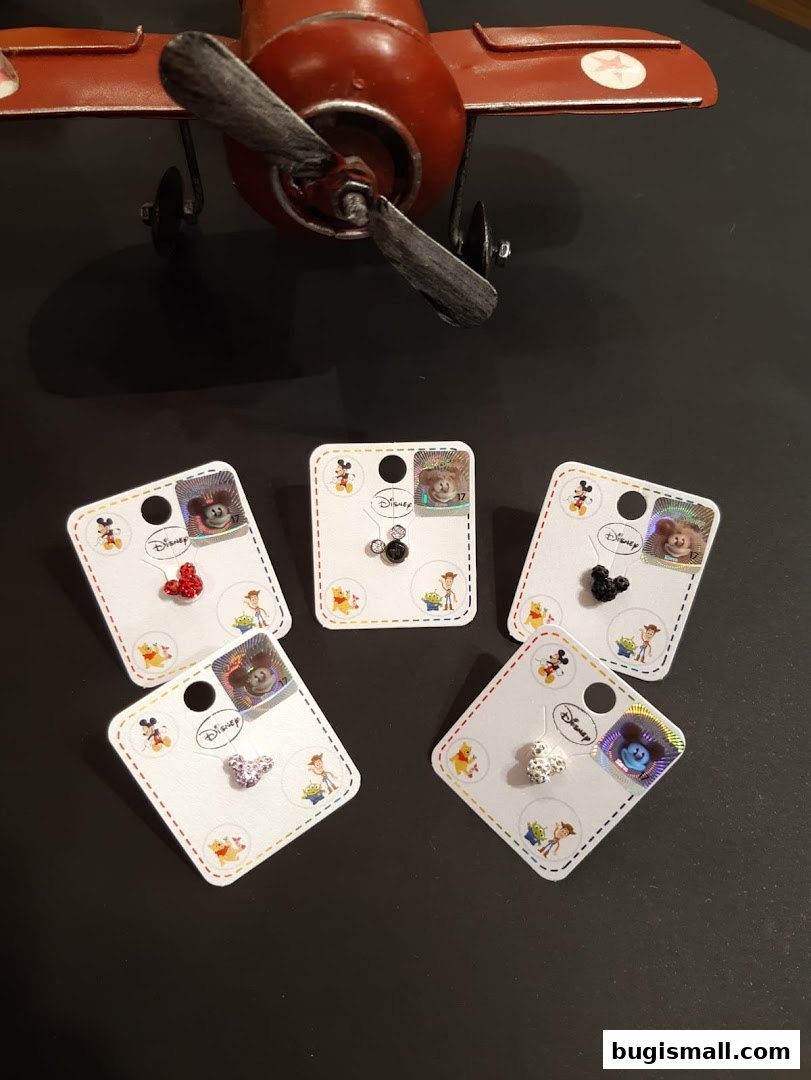 Disney-themed earrings displayed with a vintage airplane model.