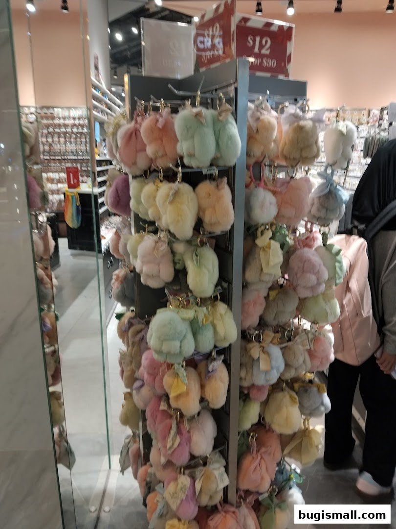 A display of fluffy, pastel-colored keychains and small pouches with bows.