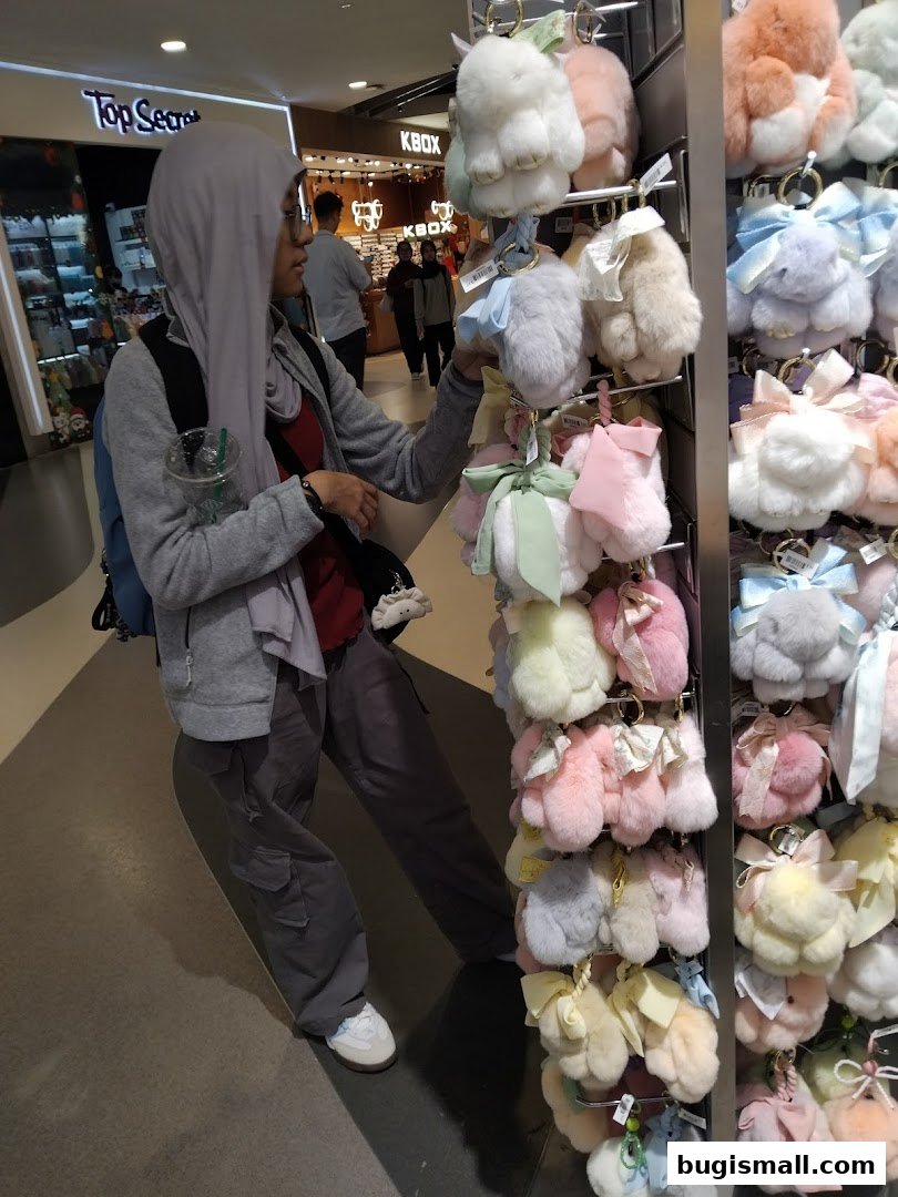 A person is browsing a display of fluffy bunny keychains in a store.