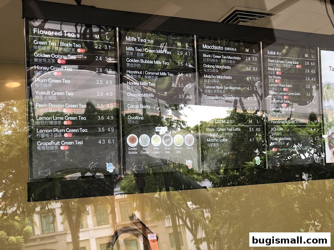 A menu board for KOI Thé displaying various flavored teas, milk teas, macchiatos, and juices with prices.