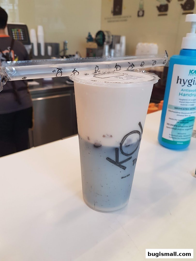 A close-up of a KOI Thé drink with straws and a bottle of hand sanitizer.