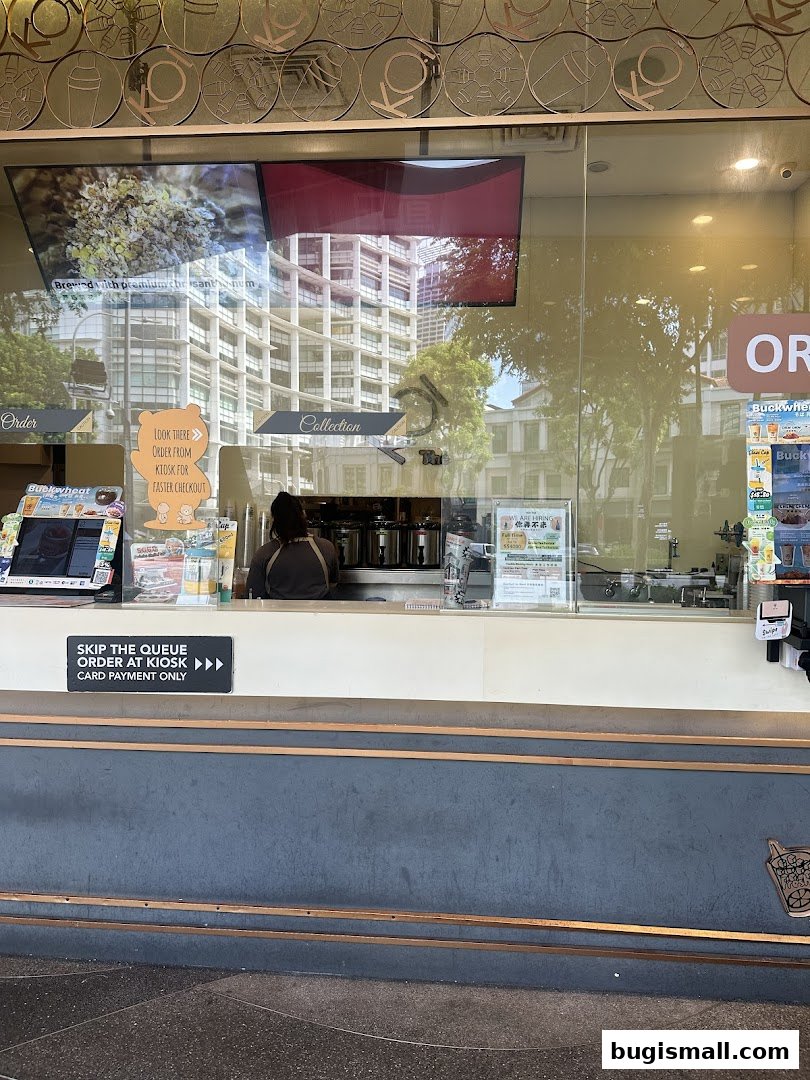 The exterior of a KOI Thé bubble tea shop with a counter and ordering kiosk.