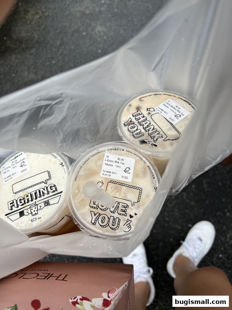 A person holding a bag of KOI Thé drinks with various messages on the lids.