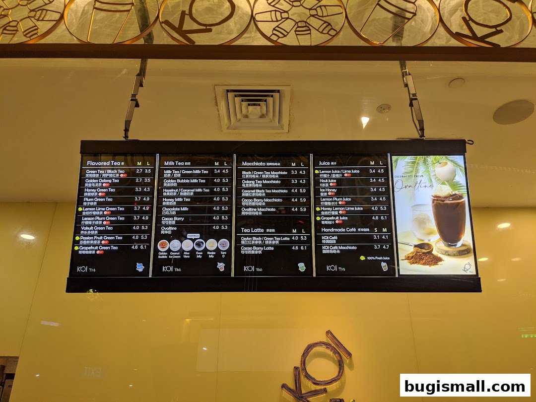 A digital menu board displaying various tea, milk tea, macchiato, and juice options with prices.