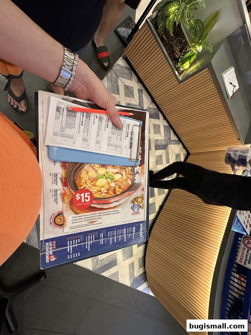 A person holding a menu from Lau Wang Claypot Delights featuring a claypot dish.
