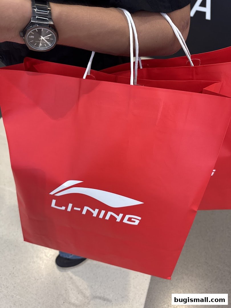 A person holding multiple red shopping bags with the Li-Ning logo.