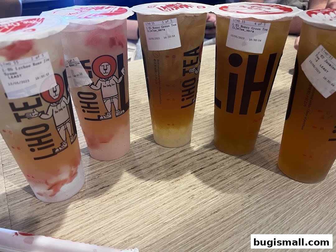 A selection of five colorful bubble tea drinks from LiHO TEA on a wooden table.