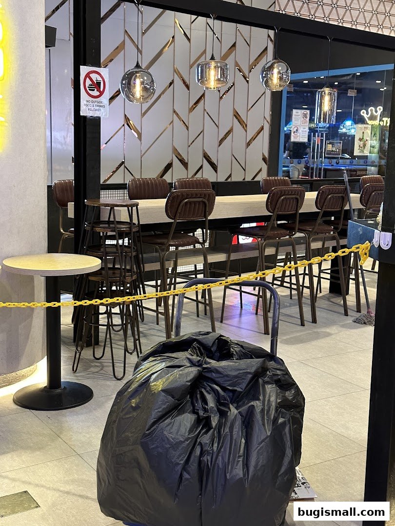 Interior seating area with high tables and chairs, decorative wall, and lighting.