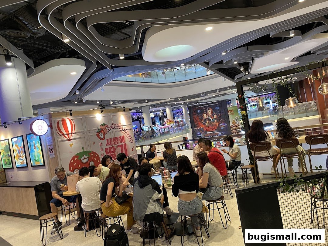 People enjoying drinks at LiHO TEA Bugis, with a Stranger Things poster in the background.