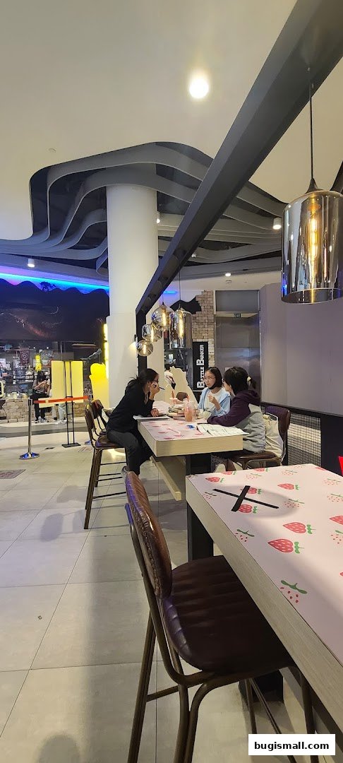 People sitting at tables inside a modern cafe with stylish lighting and decor.
