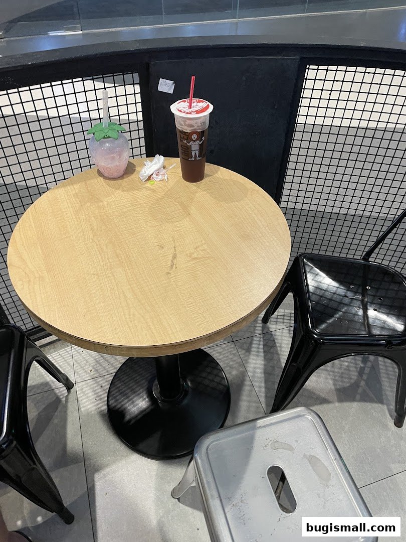 A round table with two drinks and chairs in a cafe setting.