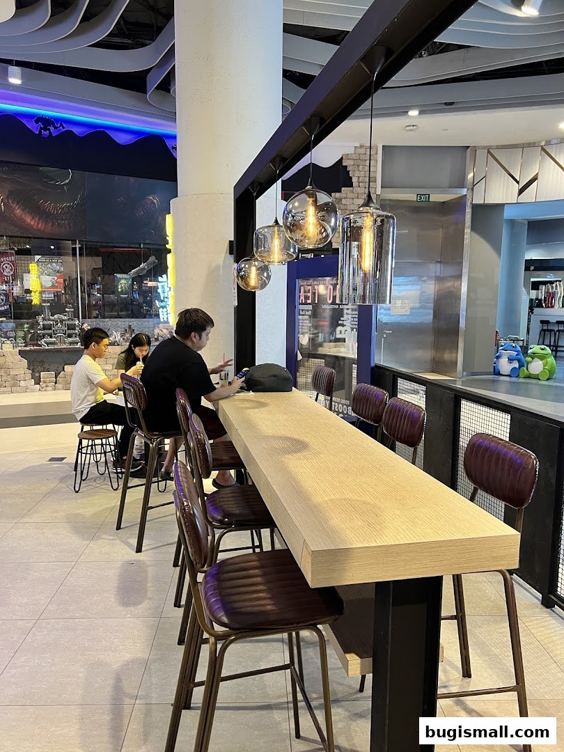 People sitting at a long counter in a modern tea shop with stylish lighting.