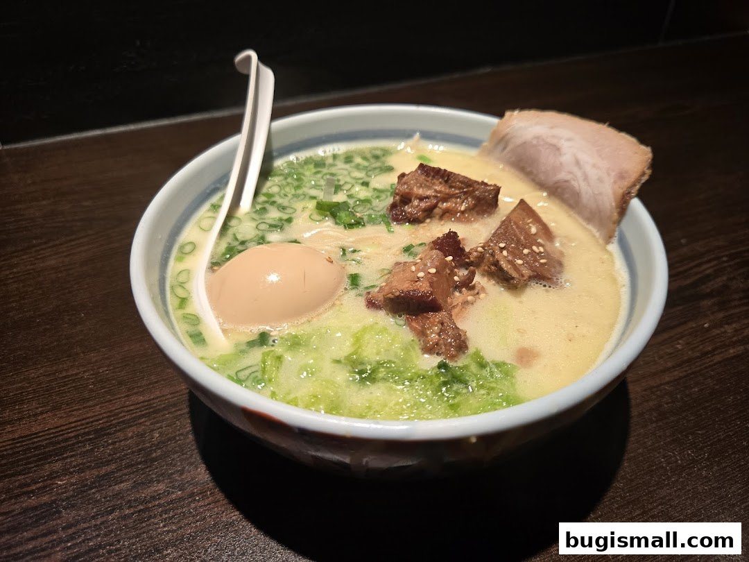 A close-up shot of a delicious bowl of ramen with chashu pork, a soft-boiled egg, and green onions.
