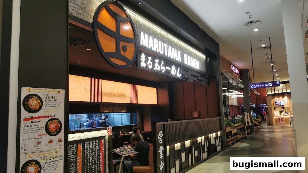 The exterior of Marutama Ramen Bugis, showcasing its signage and a menu board with ramen dishes.