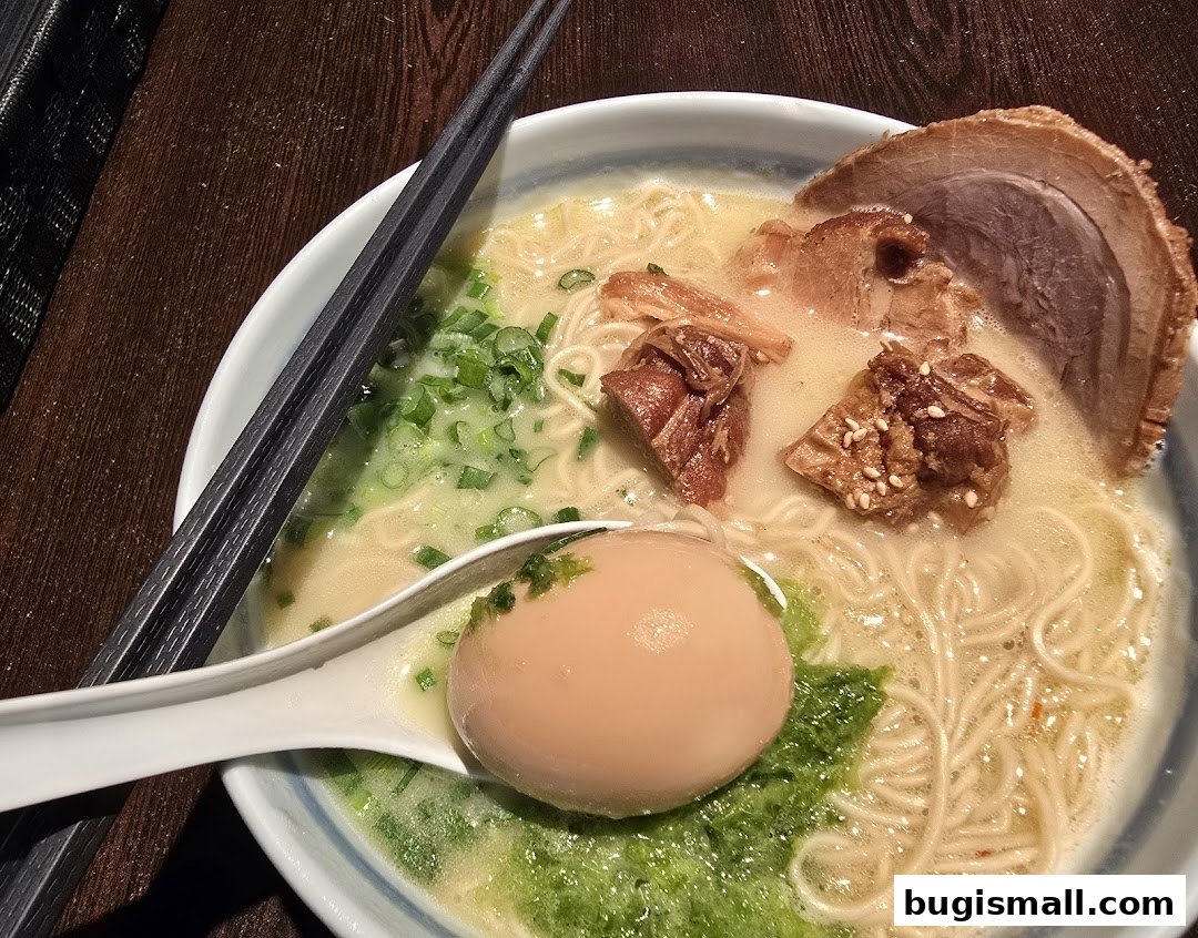 A close-up shot of a delicious bowl of ramen with tender pork, a soft-boiled egg, and green onions.
