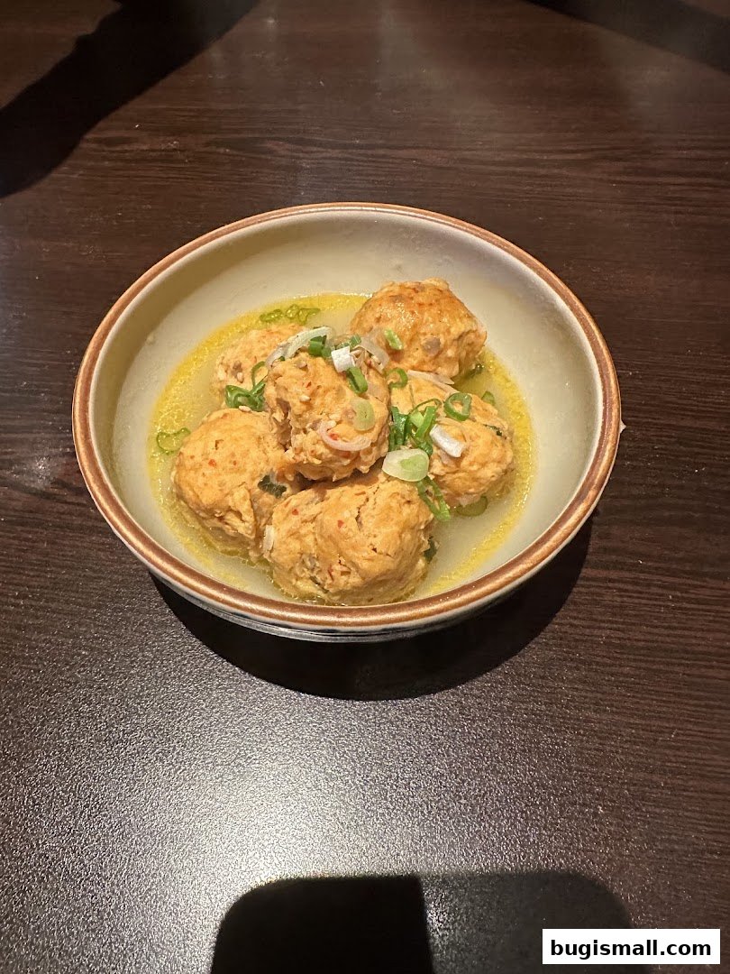 A bowl of delicious-looking meatballs in a savory broth, garnished with green onions.
