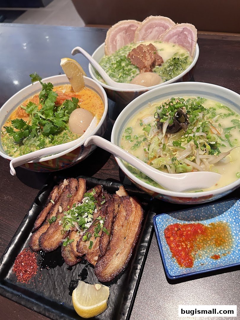 Three bowls of ramen and a plate of chashu pork with chili flakes and lemon.