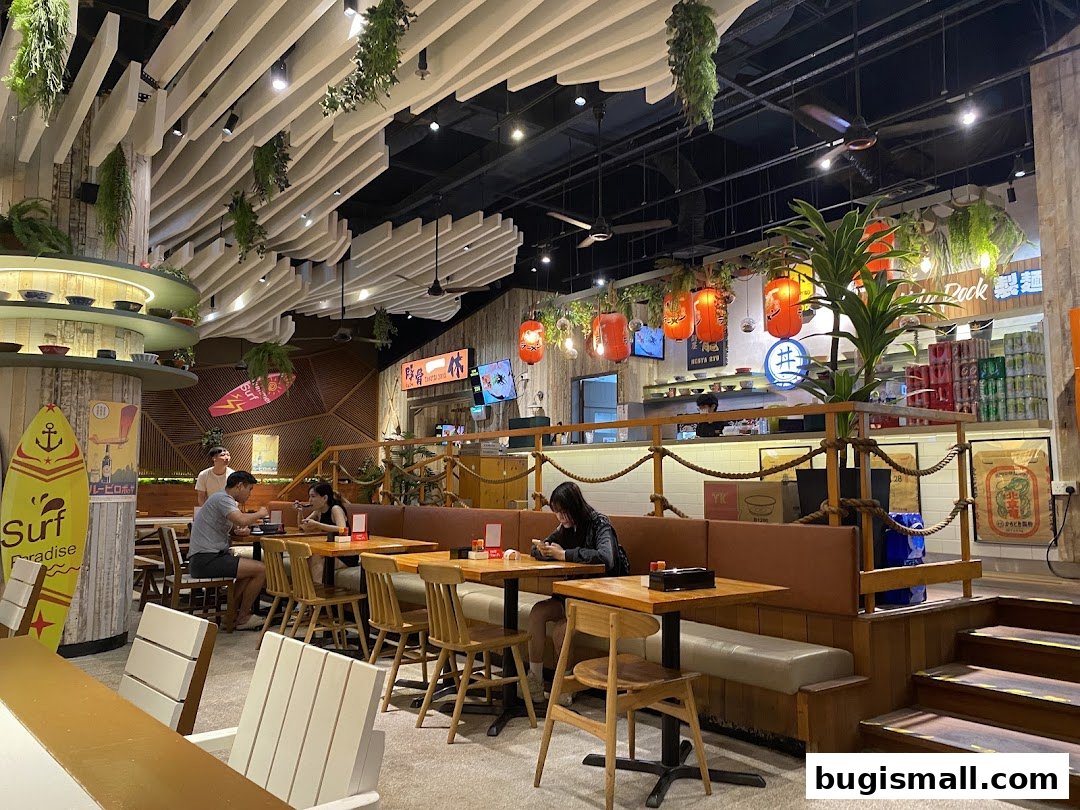Interior view of Marutama Ramen Bugis with diners seated at tables and Japanese-themed decor.