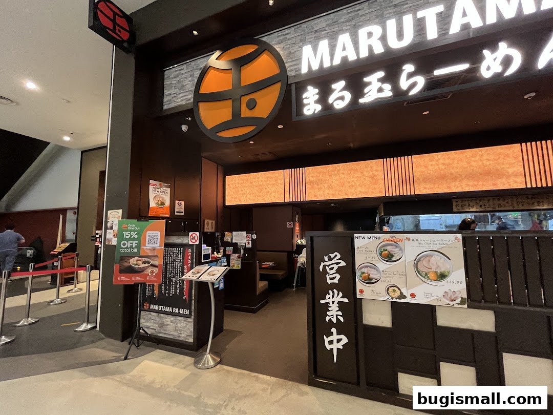 The entrance to Marutama Ramen Bugis, featuring its signage and a promotional poster.