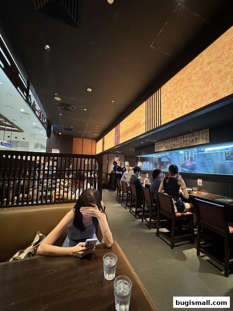 Diners seated at a counter and tables inside a Japanese ramen restaurant.