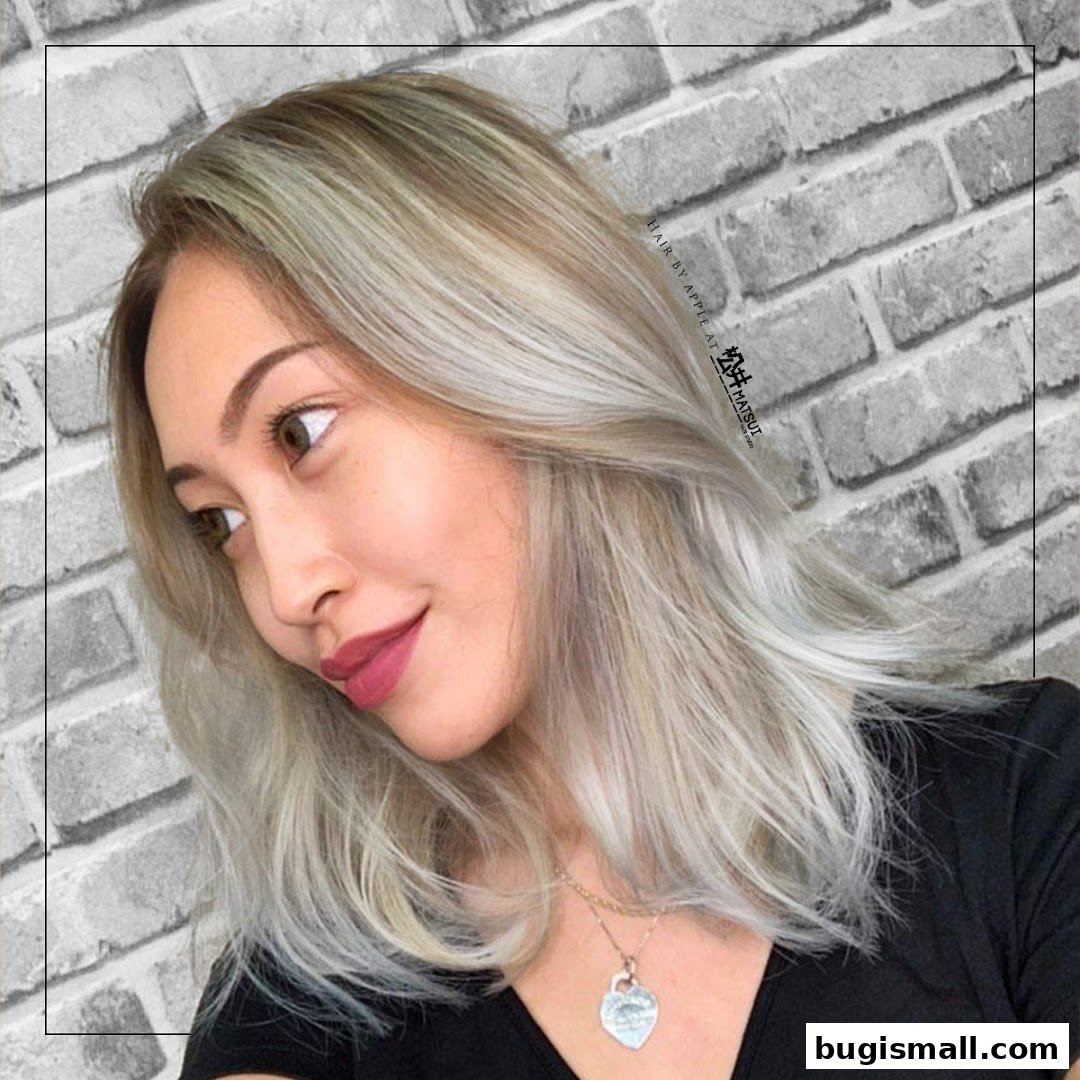 A woman with blonde hair styled by Matsui Hair Studio, against a brick background.