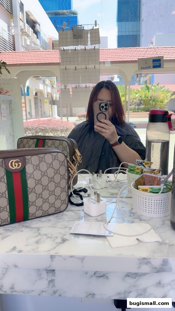 A person takes a mirror selfie in a salon, with Gucci bags and salon supplies visible.