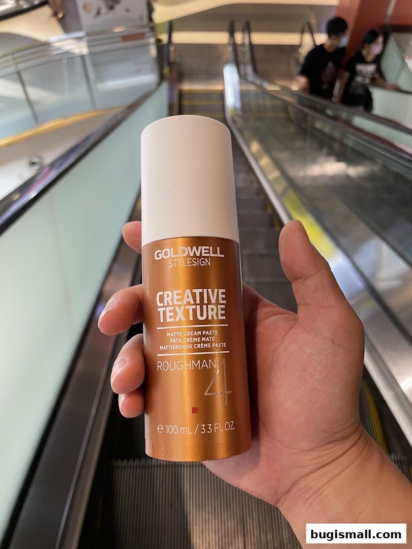 A hand holds a Goldwell StyleSign Creative Texture Matte Cream Paste.