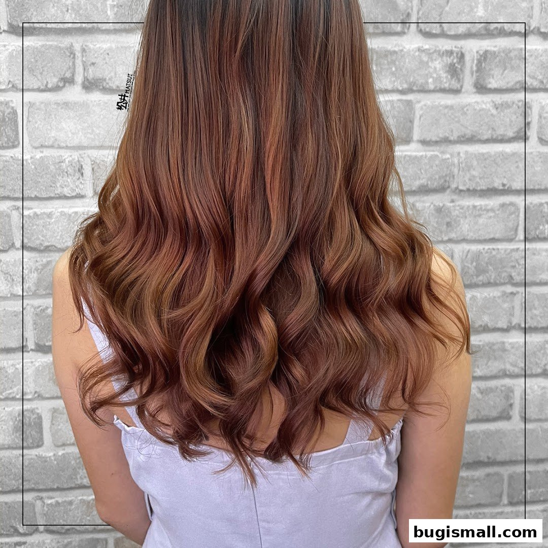 A person's back showcasing beautifully styled, wavy, reddish-brown hair with subtle highlights.